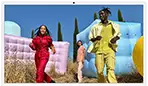 Three people in bright outfits, surrounded by colorful inflatable shapes