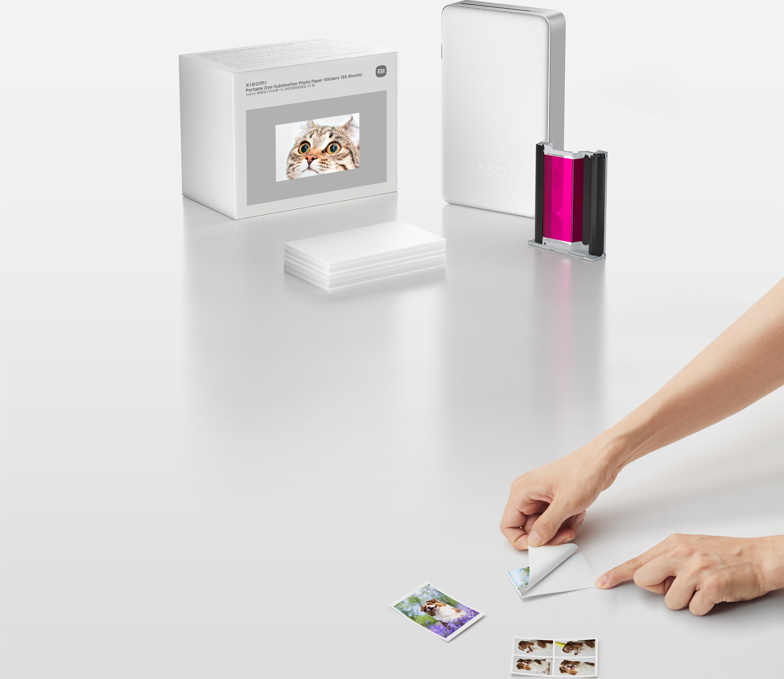 Опаковката на Xiaomi Portable Dye-Sublimation Photo Paper Stickers (50 Sheets) и ръце, които обелват самозалепваща снимка