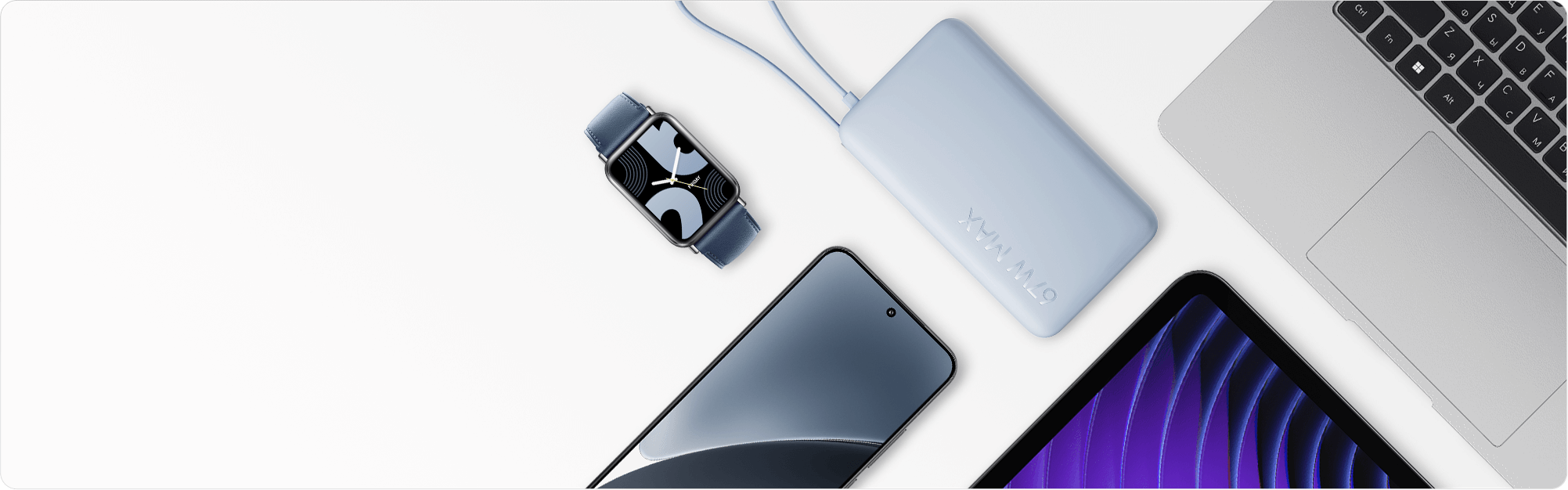 Външна батерия Xiaomi 67W Power Bank 10000 (Integrated Cable) в цвят Ice Blue върху светло бюро, до смартчасовник, смартфон, таблет и лаптоп