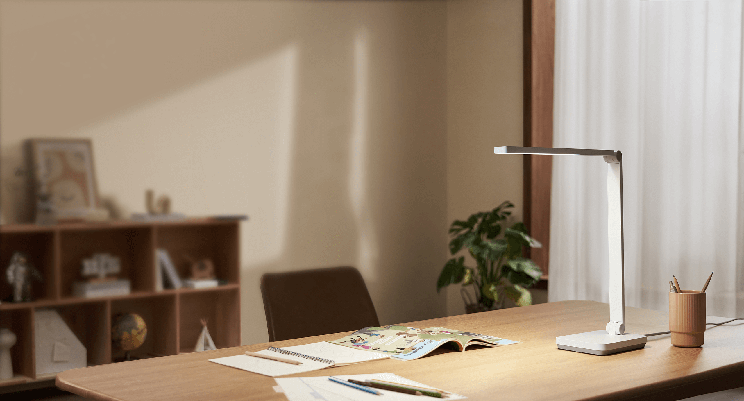 Xiaomi Desk Lamp Lite осветява равномерно широко дървено бюро с тетрадки и книга