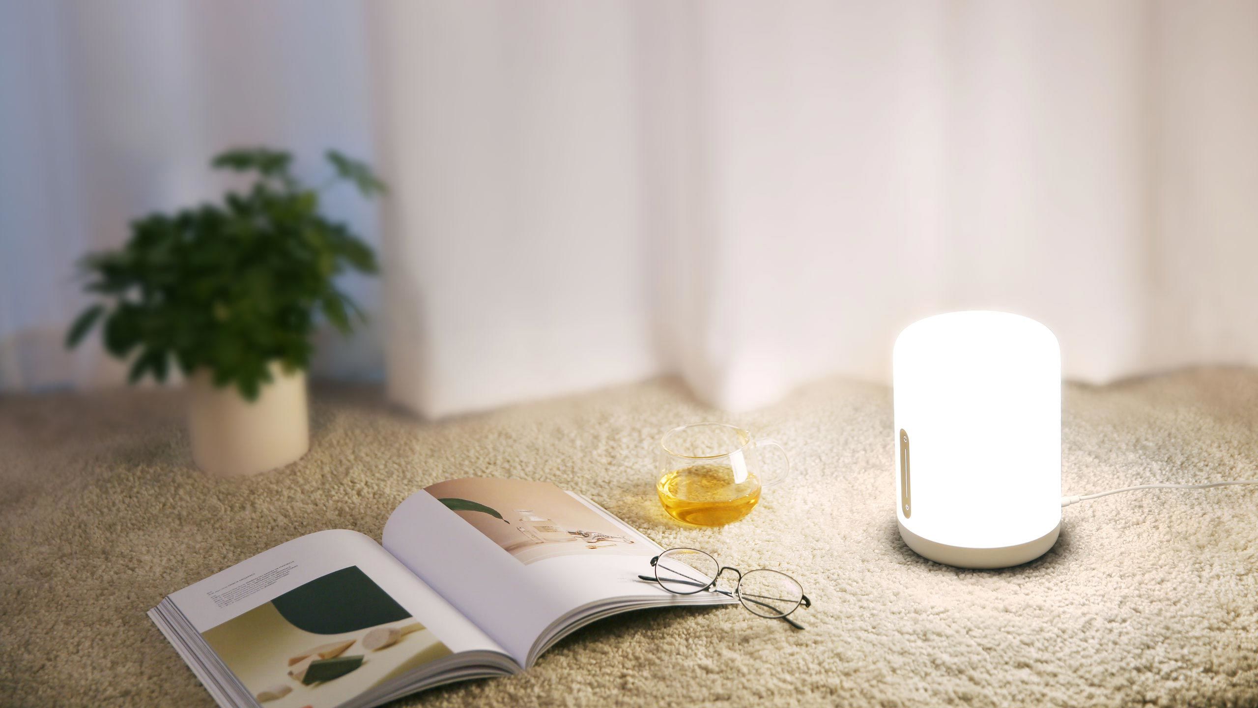 Mi Bedside Lamp 2 до отворена книга, очила и чаша чай върху килим