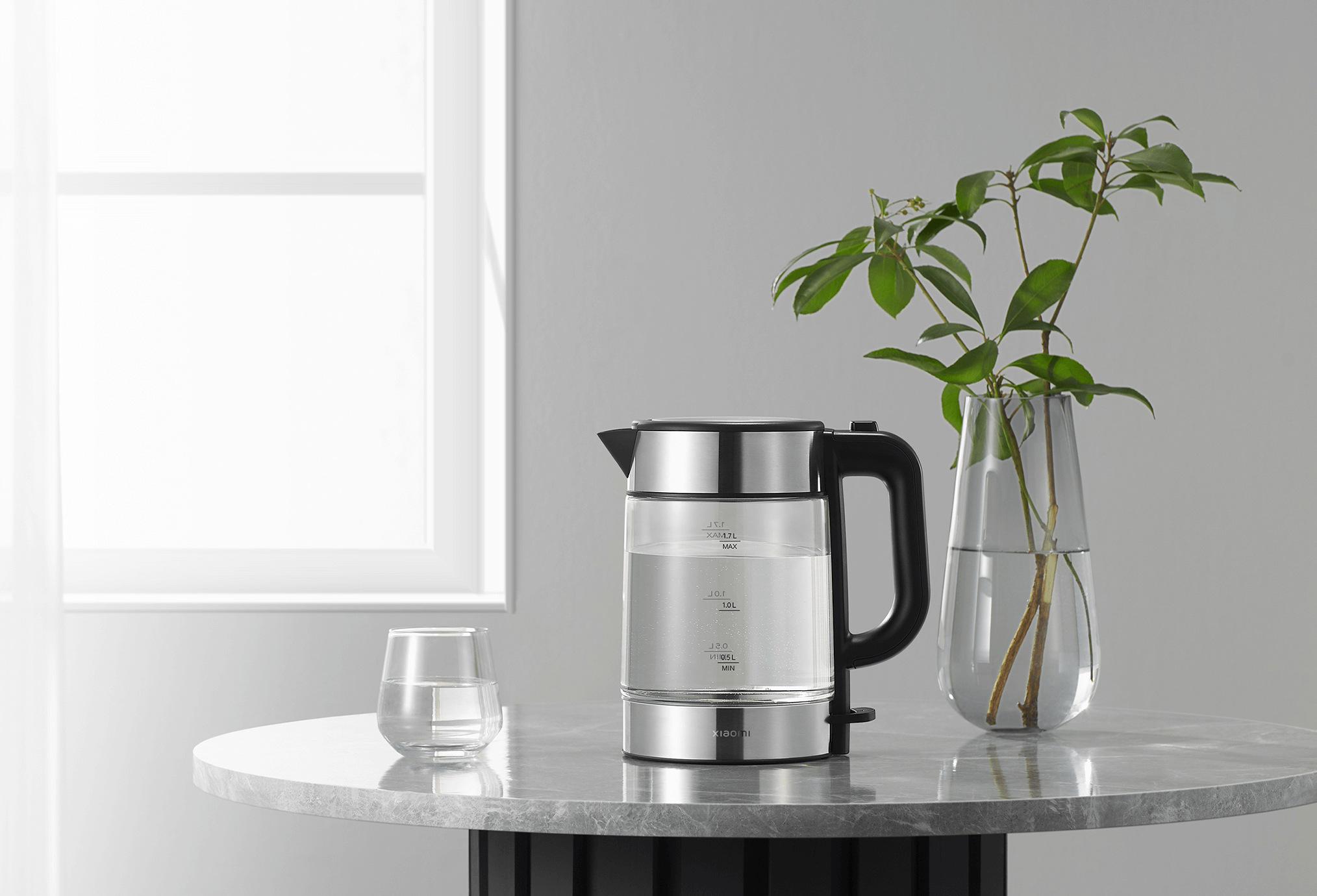 Електрическа кана Xiaomi Electric Glass Kettle върху мраморна маса до ваза със зеленина