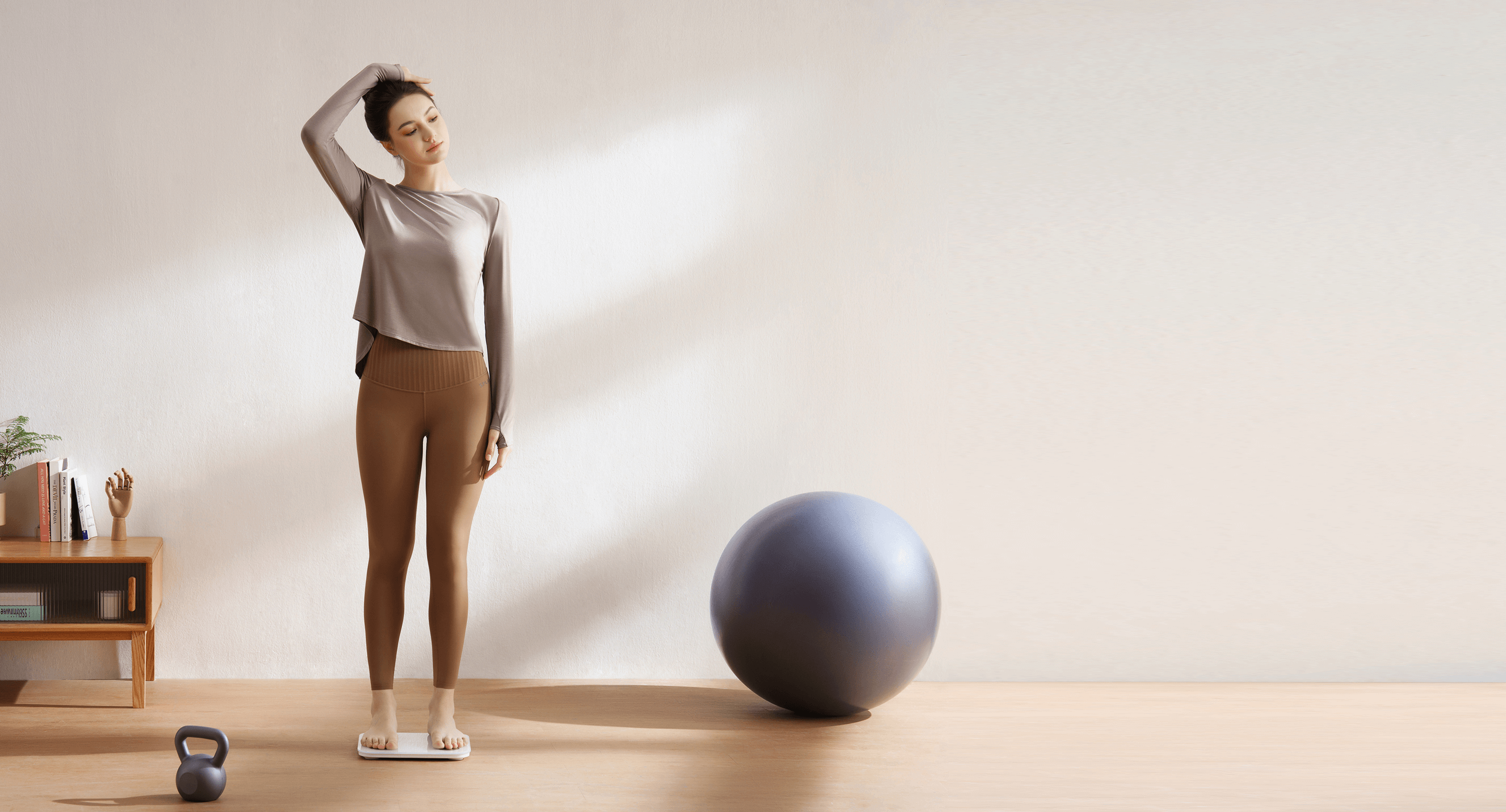 Жена се разтяга до светла стена — измерване с Xiaomi Body Composition Scale S400