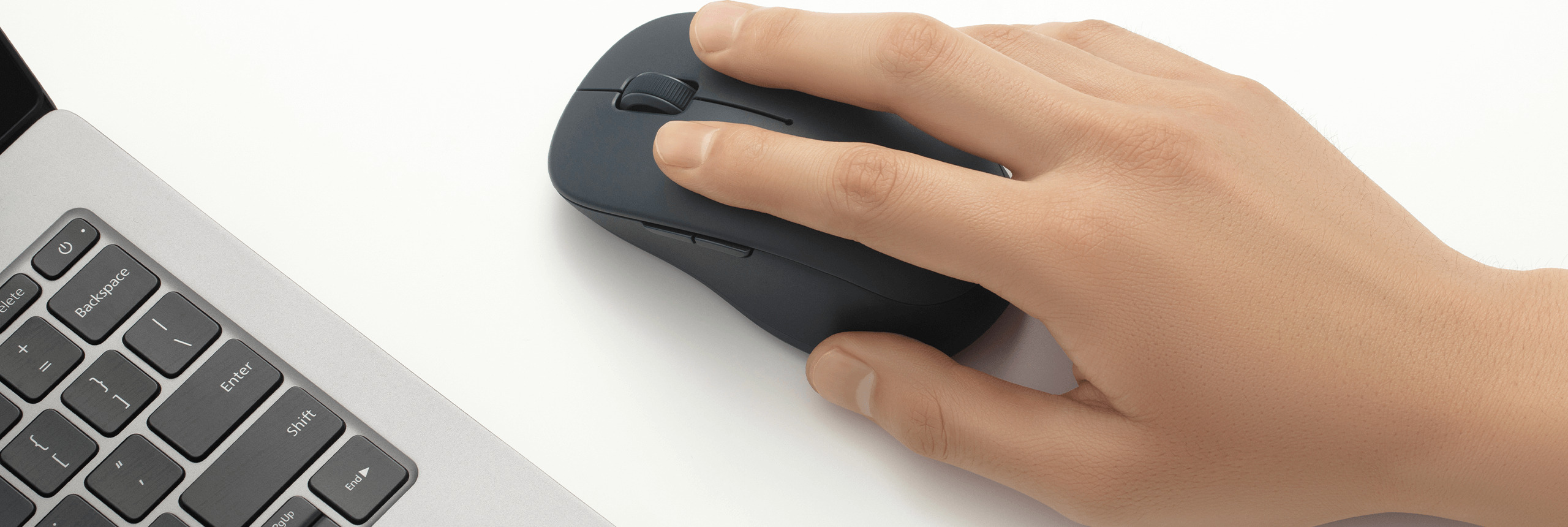 Ръка върху черната Xiaomi Dual-mode Wireless Mouse 2 до клавиатура на лаптоп