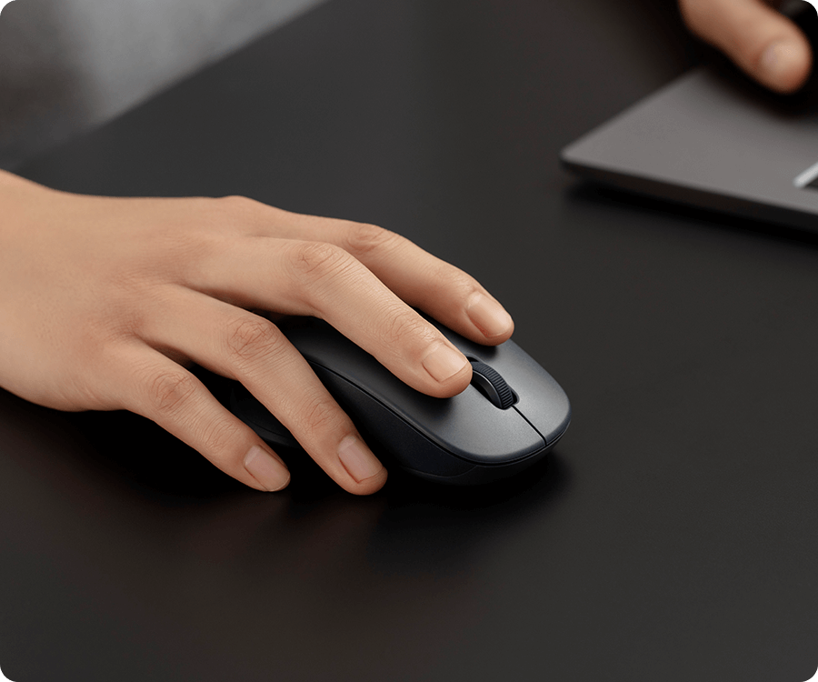 Ръка кликка тихо върху черната Xiaomi Dual-mode Wireless Mouse 2 на тъмно бюро