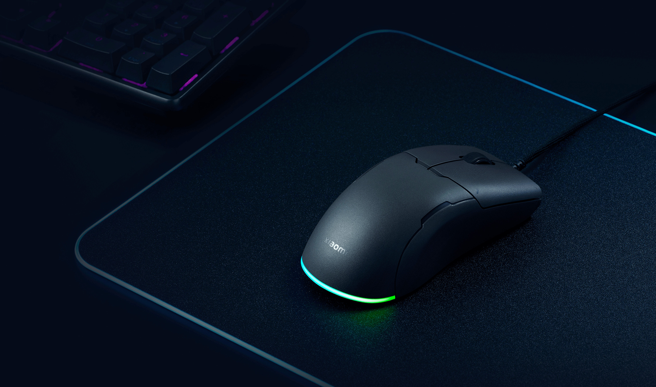 Гейминг мишка Xiaomi Gaming Mouse Lite с включено RGB осветление върху подложка до клавиатура