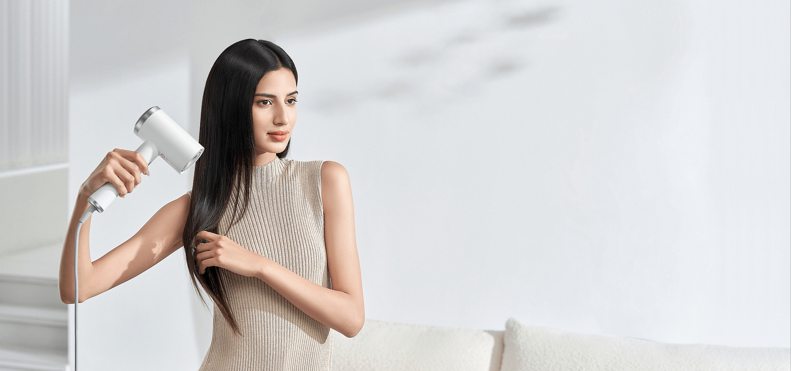 Жена суши дългата си коса със сешоар Xiaomi High-speed Ionic Hair Dryer в светла дневна