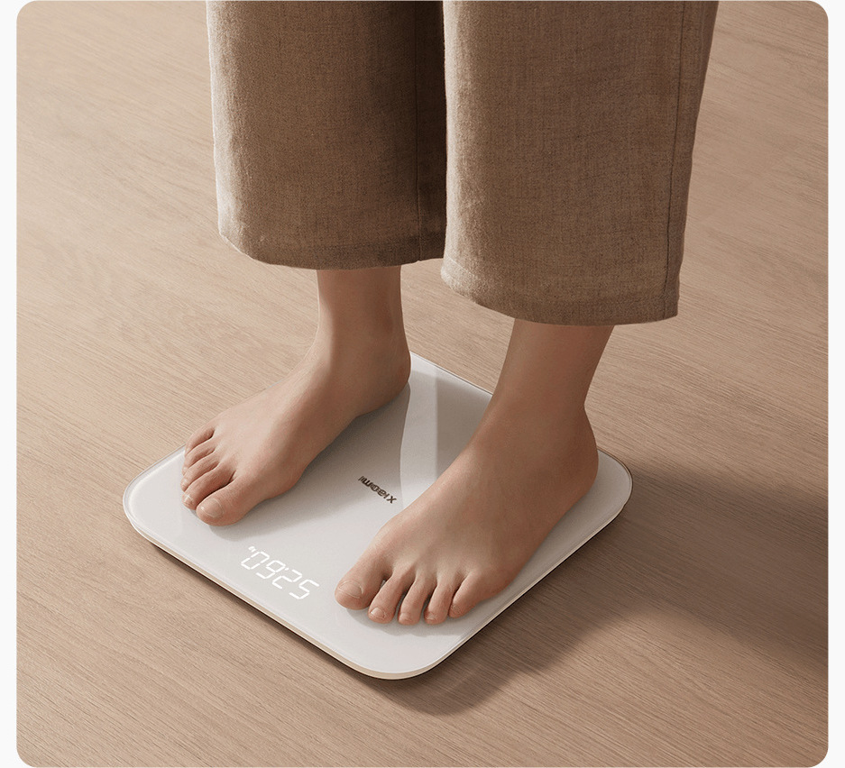 Стъпване върху белия Xiaomi Smart Scale S200 на дървен под