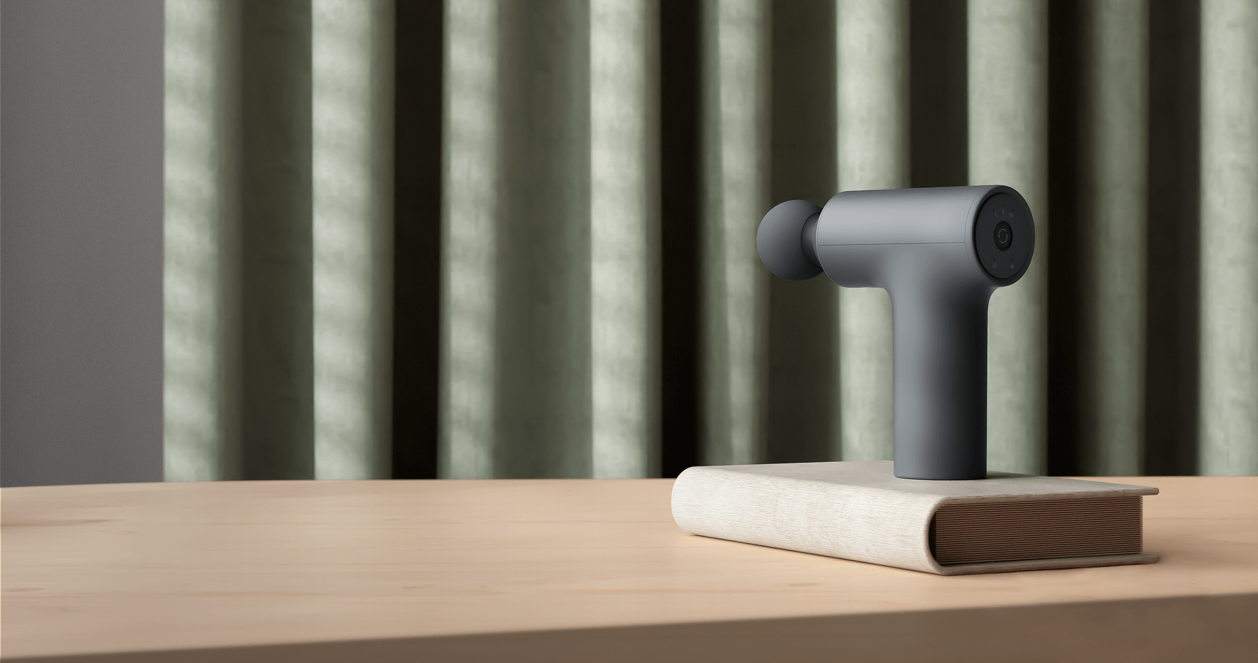 Масажен пистолет Xiaomi Massage Gun Mini 2 върху дървена маса в домашна обстановка