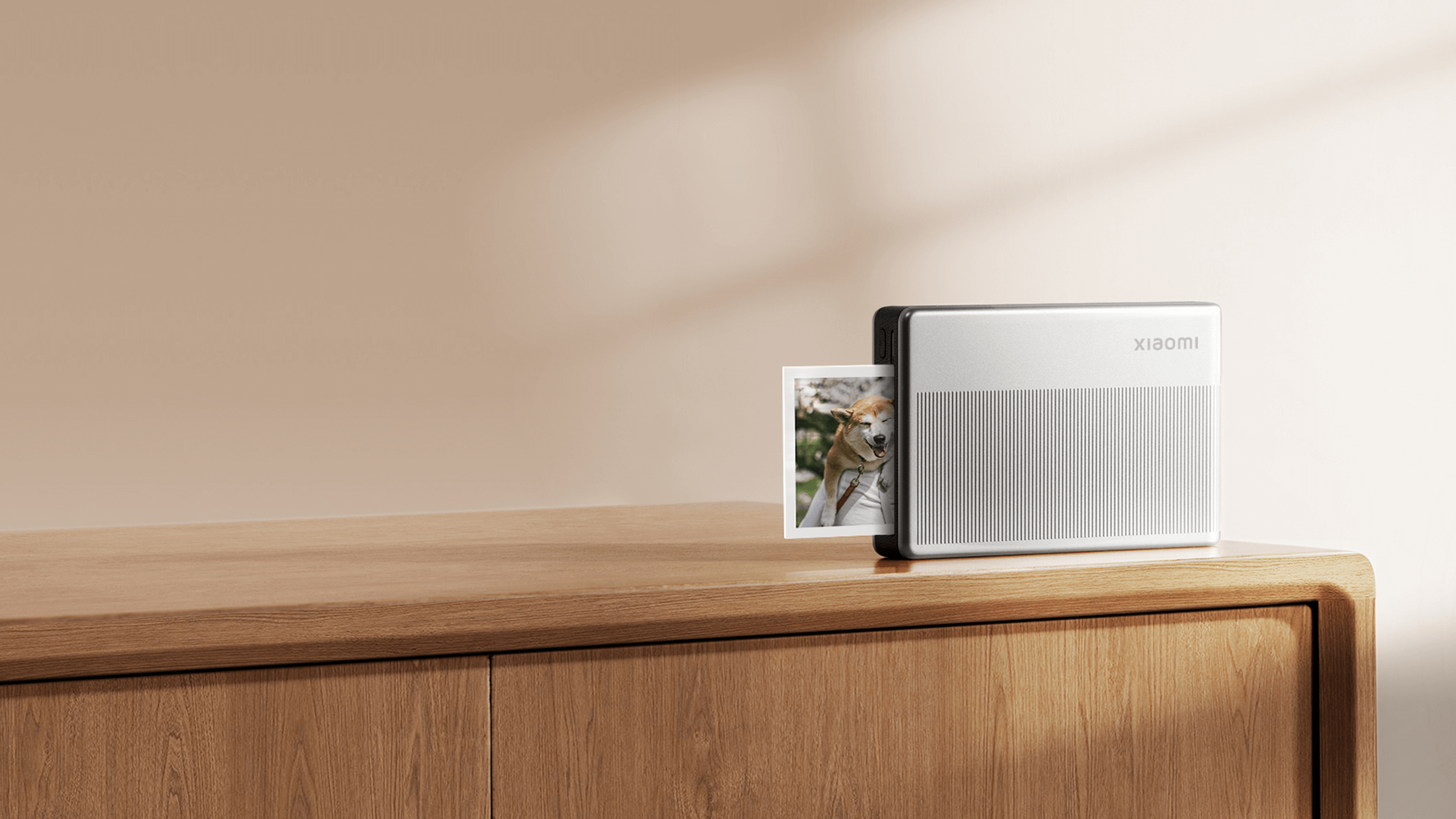 Портативен фото принтер Xiaomi Portable Photo Printer 1S върху дървен шкаф с отпечатана снимка до него