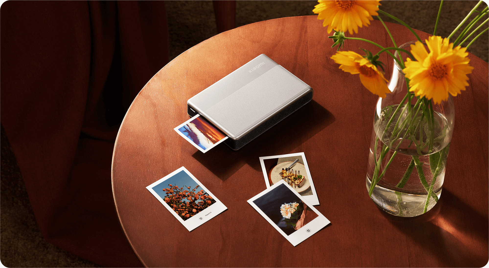 Xiaomi Portable Photo Printer 1S печата снимка върху маса с ваза цветя и готови отпечатъци