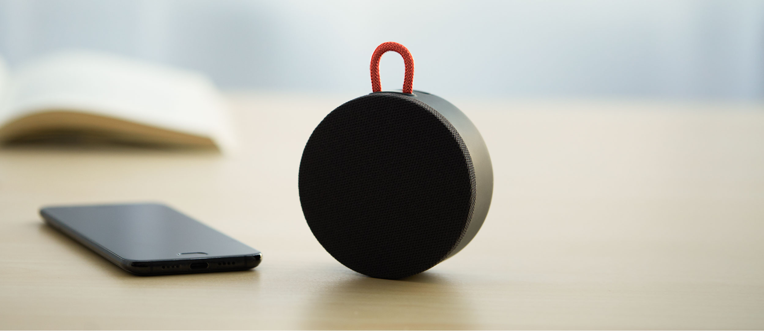 Mi Portable Bluetooth Speaker на бюро до смартфон и отворена книга