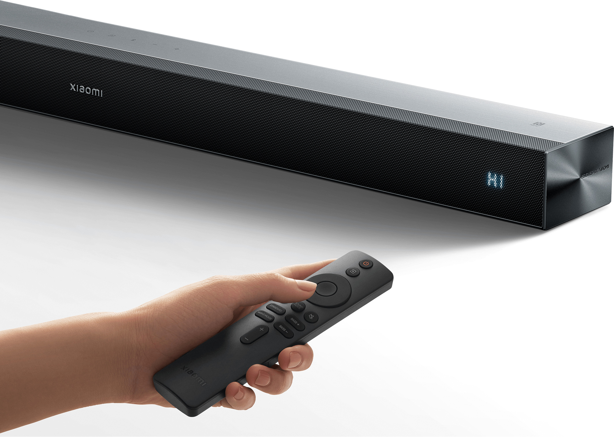 Ръка с дистанционното управление насочва към дисплея на саундбар Xiaomi Soundbar Pro 2.0 ch NS5